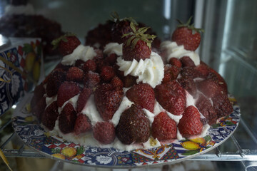 Sicilian desserts, sweets, cakes with ricotta cream, fruits, pistachio, on display in confectionery artisan shop