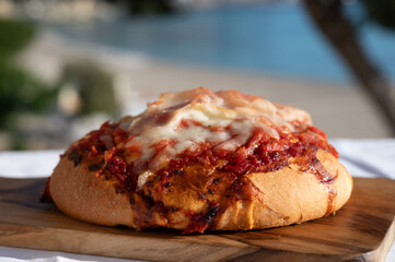 Fresh baked bread, pizza, focaccia or pala romana pizza with tomatoes, vegetables and cheese, street food in Palermo, Sicily, Italy, view on Mondello beach