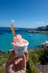 Eating of fresh made ice cream with view on blue bay of Levanza island, Egadi near Sicily, Italy