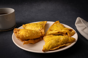 Spicy vegetarian Indian samosas served on plate as savoury snack in warm ambient light.