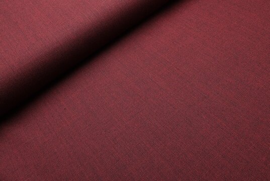Close-up of luxury burgundy cool wool suiting fabric, intricately woven with black thread to create a rich melange effect and dynamic color depth, highlighting the material's premium texture and drape