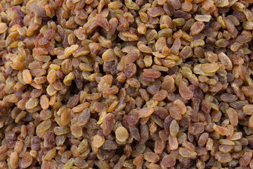 Dried golden raisins displayed in bulk at a market stall.