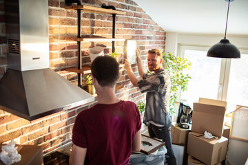 Male couple arranging new home kitchen