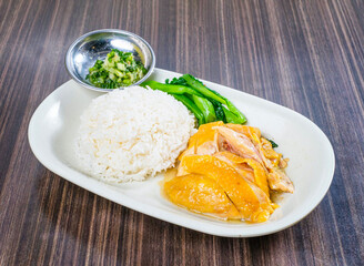 Indulge in a vibrant plate of tender Hainanese chicken rice with crisp greens and zesty chili, a truly satisfying and delicious meal bursting with authentic flavor.