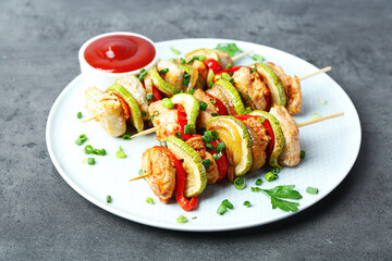 Tasty skewers with chicken, vegetables, sauce and green onion on grey table, closeup