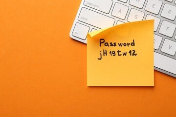 Sticky note with password and keyboard on orange background, top view. Space for text