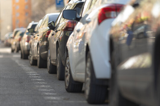 urban parking chaos, city streets crowded with parked cars, busy urban street filled with vehicles and pedestrians, chaotic city parking area with bustling crowds and vehicles