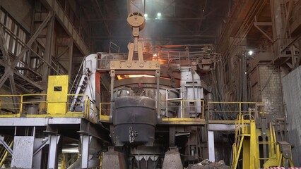 Industrial crane lifting hot metal ladle in steel mill. Stock clip