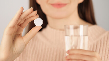 Close-up of a smiling unrecognizable woman holding a tablet and a glass of water before taking...