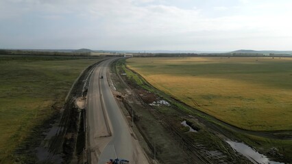 Black car driving on country road construction site. Clip