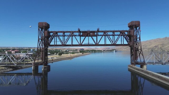 Railroad lift bridge over the Snake River in Lewiston Idaho. Closeup pan shot of the central span of the bridge in a high desert setting with a calm Snake River below.