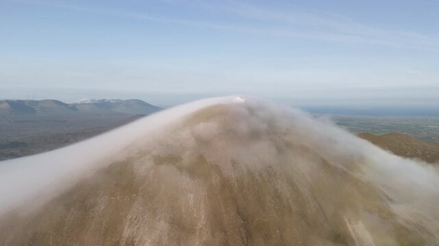 Amazing 4K aerial video of flying above and around Most Famous mountain in Ireland - Croagh Patrick in windy weather, with moving fog and clouds with breathtaking views around, Westport, Ireland