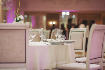 Elegant dining table set for a special celebration in a beautifully decorated venue with soft lighting and floral arrangements near evening time