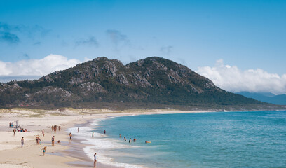 A long wooden pier or bridge extends into the blue sea or lake under a bright summer sky
