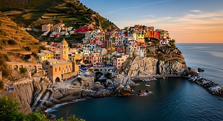 Vibrant, colorful houses cling to a dramatic cliffside overlooking a tranquil sea at sunset.