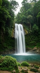 Naklejka premium Lush greenery surrounds a tranquil waterfall cascading into a serene pool of turquoise water.