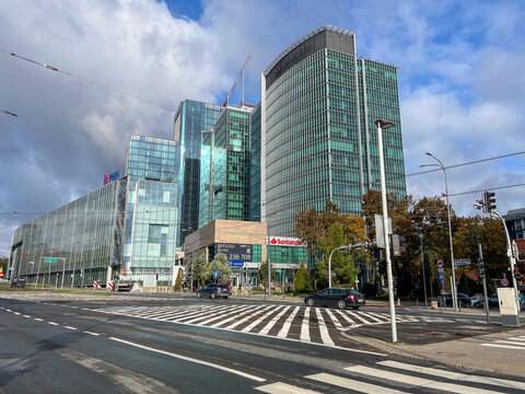 Poznan, Poland - October 10, 2025: Modern glass office skyscrapers, prominently displaying Santander and PHN corporate logos, shape a dynamic, bustling urban streetscape