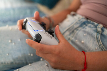 Person hands holding controller playing video game at home