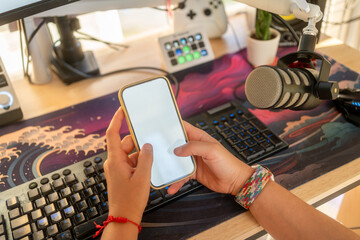 Person holding smartphone near streaming setup