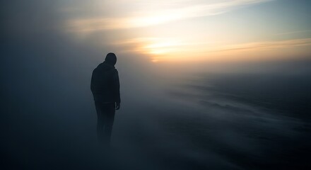 Silhouette of a person standing in a misty landscape at sunset.