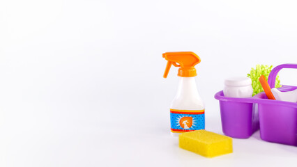Cleaning supplies arranged on a white background, featuring a spray bottle, sponge, and purple...