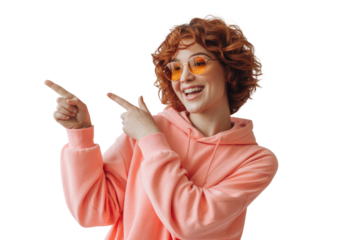 Young woman with curly red hair wearing a pink hoodie pointing to the side