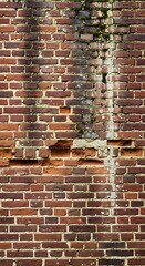 A weathered brick wall displays various shades of red and brown, showing signs of age and repair.