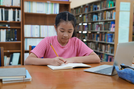 Student learning online class by using laptop computer and writing notebook at workplace, E learning and online working concept.