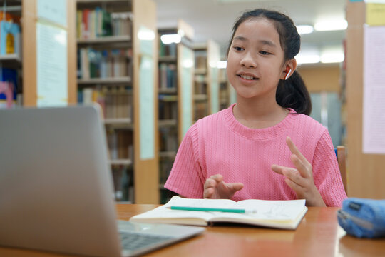 School student girl having video call on her computer in library at school.