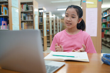 School student girl having video call on her computer in library at school.