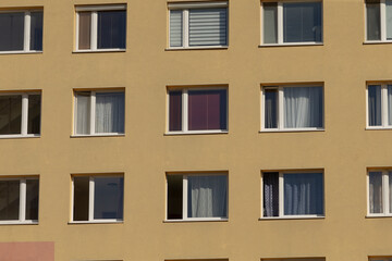 modern city buildings featuring uniform yellow window panes with symmetry, contemporary urban architecture showcasing symmetrical facades with muted yellow window panels and uniform window panes