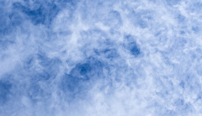 Blue sky filled with soft, wispy clouds creates a calm, expansive mood
