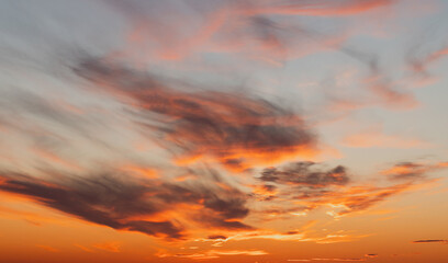 A breathtaking sunset scene features warm orange clouds drifting across sky