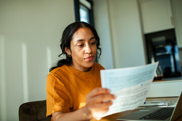 Young adult woman reviewing documents at home