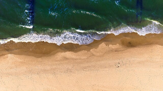 Aerial view of calm Baltic Sea waves on a sunny spring day in Sarbinowo, Poland.
