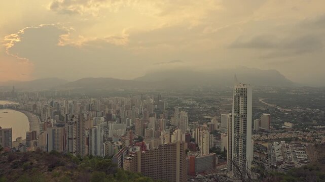 Aerial view of benidorm skyline in spain, showcasing the bustling city with its numerous skyscrapers, sandy beaches, and the mediterranean sea during a beautiful golden hour sunset