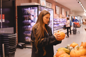 Unrecognizable girl choosing pumpkin in supermarket near shelf with organic fruits and vegetables. Woman shop eco market. Bio farm grocery store. Buyer girl put organic meal cart. Person keep raw diet