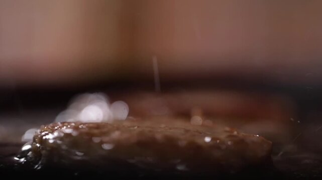 Macro shot of stir frying meat patty on pan. Meat sizzling on pan.