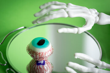 A skeleton hand reaching for a vivid glass eye with intricate blood vessels