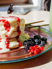 Fluffy souffle pancakes with cream and berries served with glass of matcha drink
