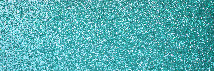 Sparkling teal glitter texture with shimmering details in a close-up abstract background.