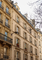 Parisian residential building facade with traditional windows, shutters, and balconies in Paris, France. Paris, France