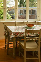 Dining room interior with floral tablecloth table and wooden chairs near a window. Cotswolds countryside, England