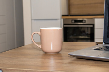 Soft pink mug on wooden table in modern kitchen, natural light and cozy atmosphere. Perfect for themes of coffee, morning routine, relaxation, and minimalist lifestyle.