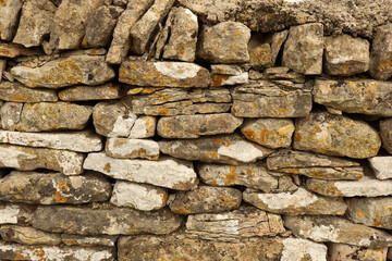 Dry stone wall texture showing stacked rocks with varying shapes, colors, and rustic surface patterns