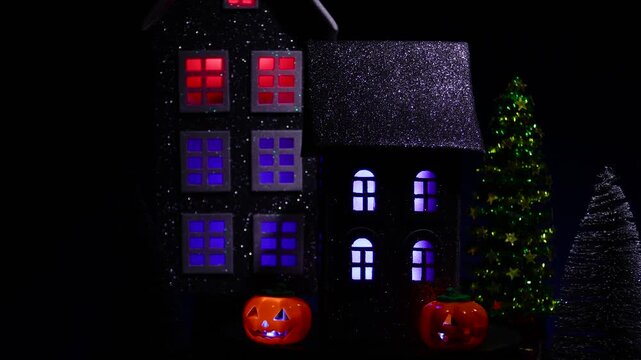 Against the backdrop of a large house, a house surrounded by glowing pumpkins and a candle rotates 