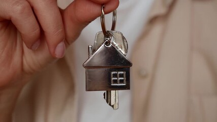 A woman holds the keys to a house with a house-shaped key ring. A symbol of ownership, trust, a new home, real estate. - Powered by Adobe