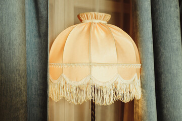 beautiful Lampshade in bedroom.old floor lamp with a hole with a fringe.Room decoration in retro style, furniture details and old lamps by the window.Vintage floor lamp