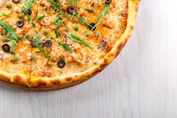 Cheesy Italian pizza with olives, capers, and fresh arugula