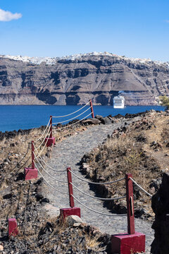 Scenic Volcanic Trail with Rope Barrier Overlooking Santorini Caldera, Cruise Ship, and Distant Fira Village